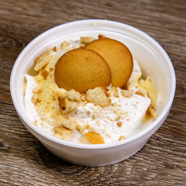 Double J Eatery's banana pudding dessert in a white bowl, topped with vanilla wafers and crumbs.