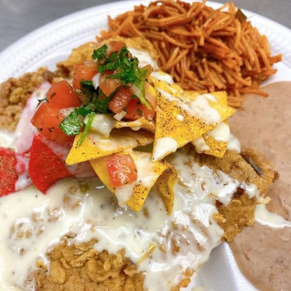 A Double J Eatery plate with fried chicken, rice, beans, and nachos topped with pico de gallo.