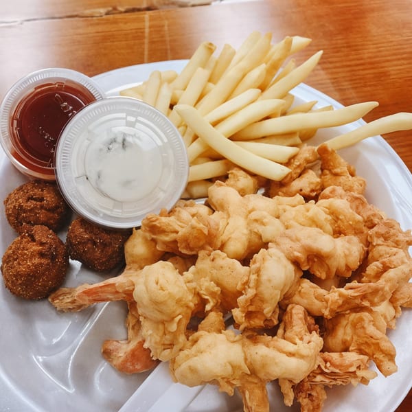 A Double J Eatery platter with fried shrimp, hush puppies, fries, and dipping sauces.