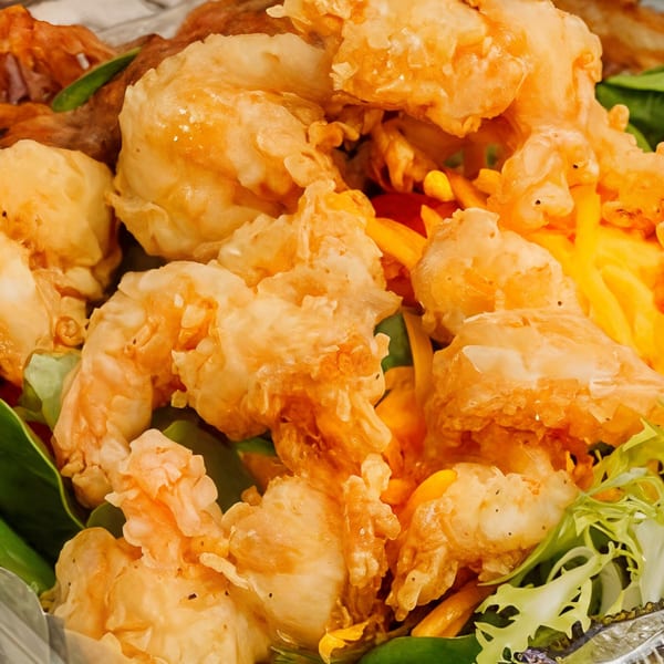 Crispy fried shrimp and chicken pieces with green lettuce and yellow bell peppers.